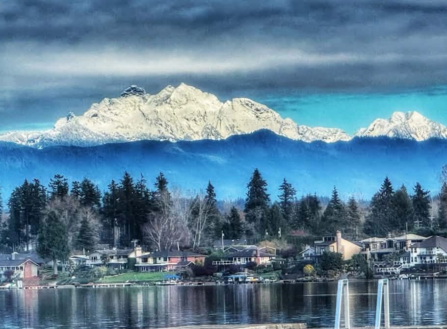 Snow-covered Cascade peaks rising above homes along the Lake Stevens shoreline.
